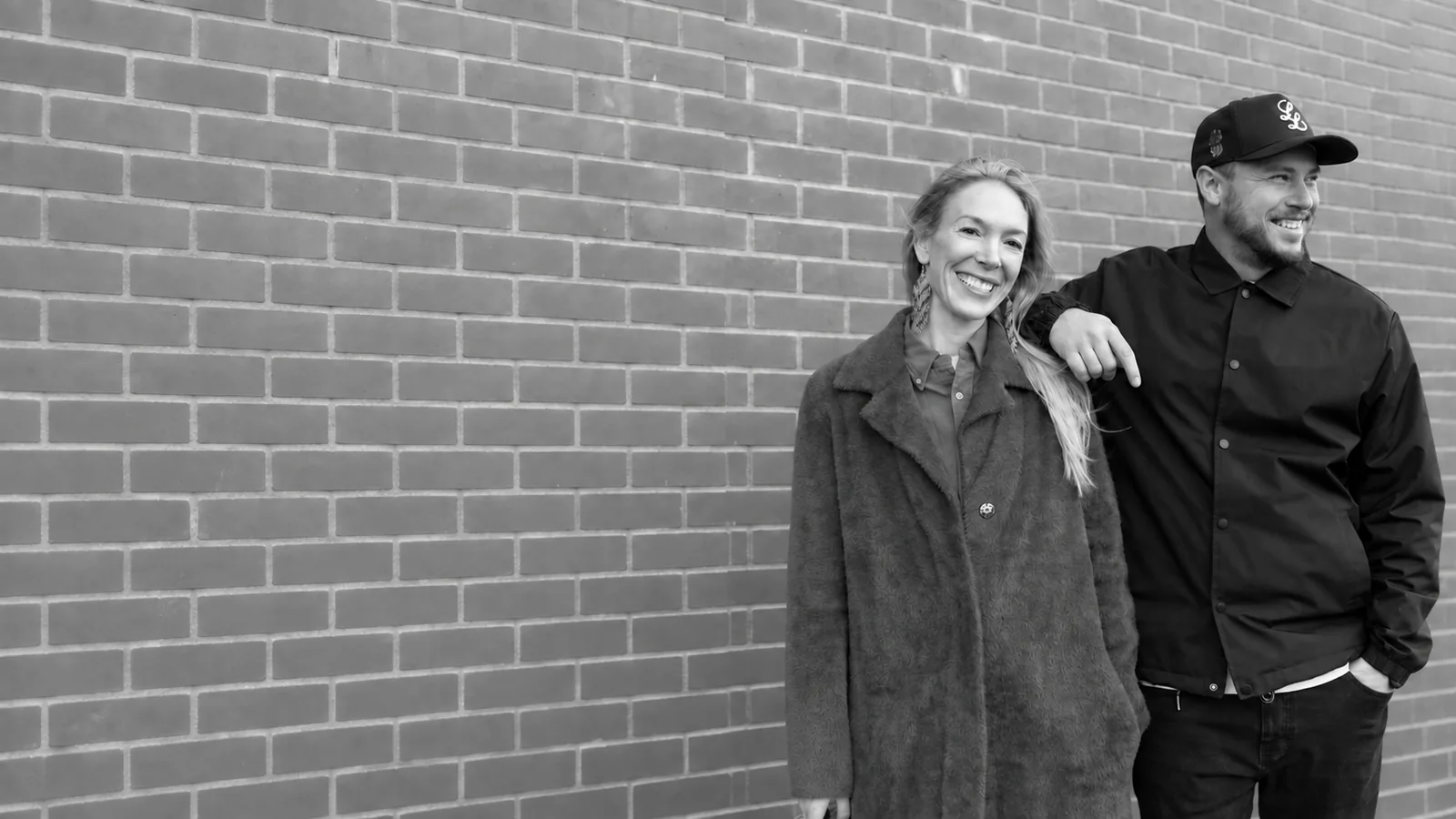 Natalie and Jesse standing together in front of a brick wall